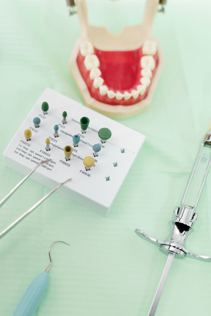 Close-up of dental tools and a dental model on a mint green surface.